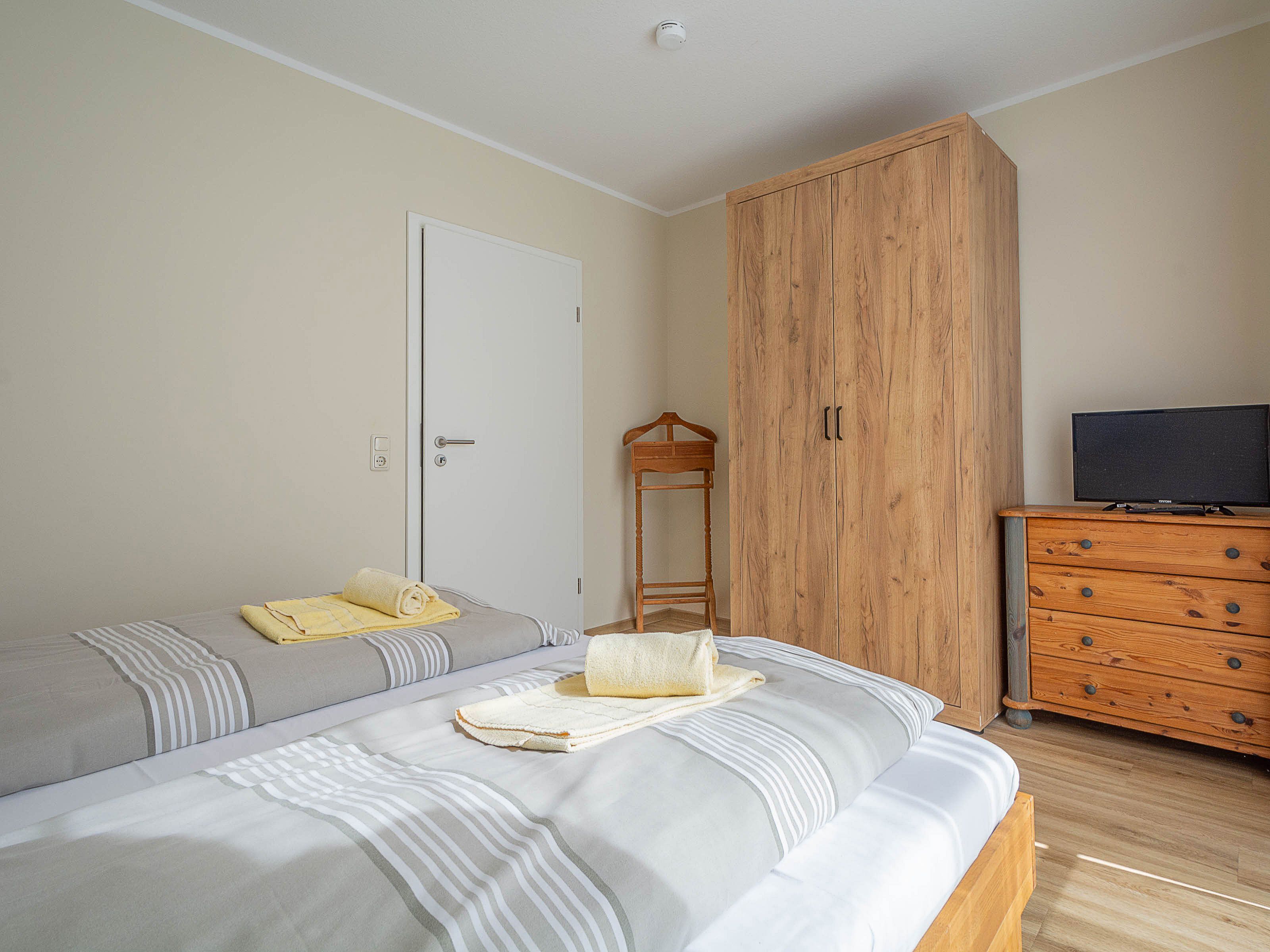 Un dormitorio con cama, armario de madera, cómoda y televisor.
