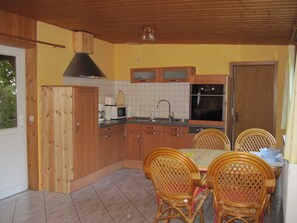 Una cocina con armarios de madera, un microondas, un fregadero y una mesa de comedor con sillas de mimbre.