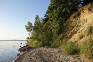 Ein sandiger Strand mit einem roten Boot und einer felsigen Küste.