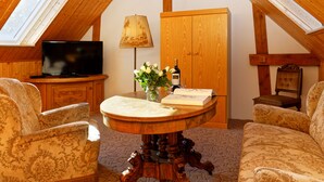 A cozy room with a wooden ceiling, a round table with a vase of flowers, a television, and two patterned armchairs. - Small cottage on the forest and hunting lodge - Forest & Jagdgut (Lütow)