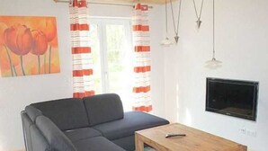 Un salon comprenant un canapé d’angle, une table basse en bois et un téléviseur à écran plat fixé au mur.