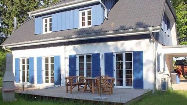 Un bâtiment à deux étages, doté d’un toit plat et de volets bleus aux fenêtres.