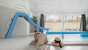A swimming pool with a blue slide, a potted plant, and a straw hat on the floor. - Gorgeous home in Tisvildeleje with sauna (Tisvildeleje)
