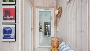 A hallway with a wooden door, a bench with a striped pillow, and two framed posters on the wall. - Gorgeous home in Tisvildeleje with sauna (Tisvildeleje)