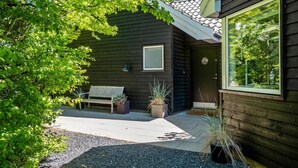 A wooden house with a bench, potted plants, and a door. - Gorgeous home in Tisvildeleje with sauna (Tisvildeleje)