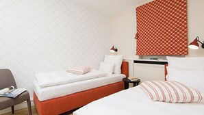 Ett hotellrum med två sängar, ett skrivbord och en stol.