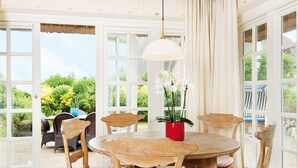 En matplats med ett runt träbord, sex stolar och en röd vas med vita blommor.