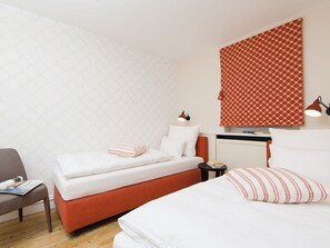 A hotel room with two beds, a desk, and a chair.