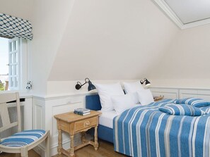 Une chambre à coucher avec un lit, des tables de chevet, une chaise et une fenêtre.