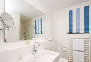 A modern bathroom with a large mirror, a sink, and a shower area.