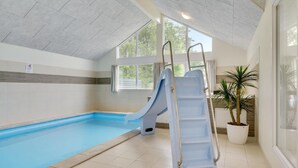 An indoor swimming pool with a blue slide, a ladder, and potted plants. - Gorgeous home in Frederiksværk with sauna (Frederiksværk)
