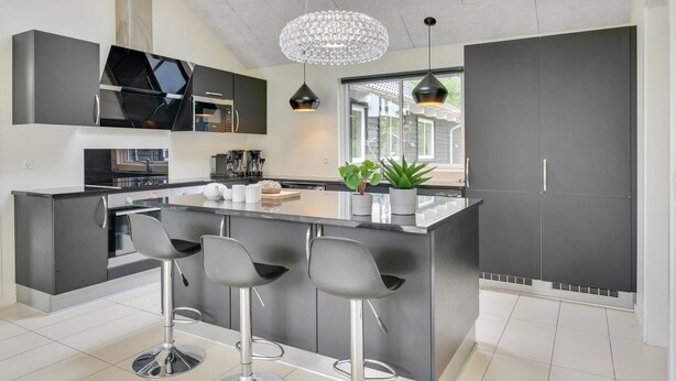 A modern kitchen with a central island, bar stools, a chandelier, and a large window. - Gorgeous home in Frederiksværk with sauna (Frederiksværk)