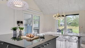 A modern kitchen with a large island, clear glass chairs, and a view of the outdoors. - Gorgeous home in Frederiksværk with sauna (Frederiksværk)