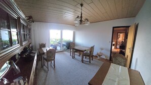 Un comedor con mesa y sillas, una ventana con cortinas y un ventilador de techo.