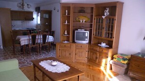 A cozy living room with a wooden table, a television, and a dining area with chairs and a table. - Holiday apartment with terrace (Kampor)