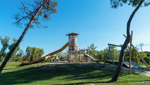 Un parque infantil con tobogán, estructuras para escalar y columpios.