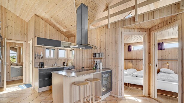 A modern cabin interior with a kitchen, dining area, and a bedroom.