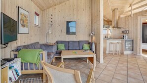 A wooden interior with a sofa, coffee table, and bar stools.