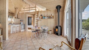 A wooden interior with a dining area, kitchen, and a large window.