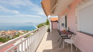 A balcony with a table and chairs, overlooking a coastal town and the sea. - 1 bedroom awesome apartment in Podaca (Podaca)