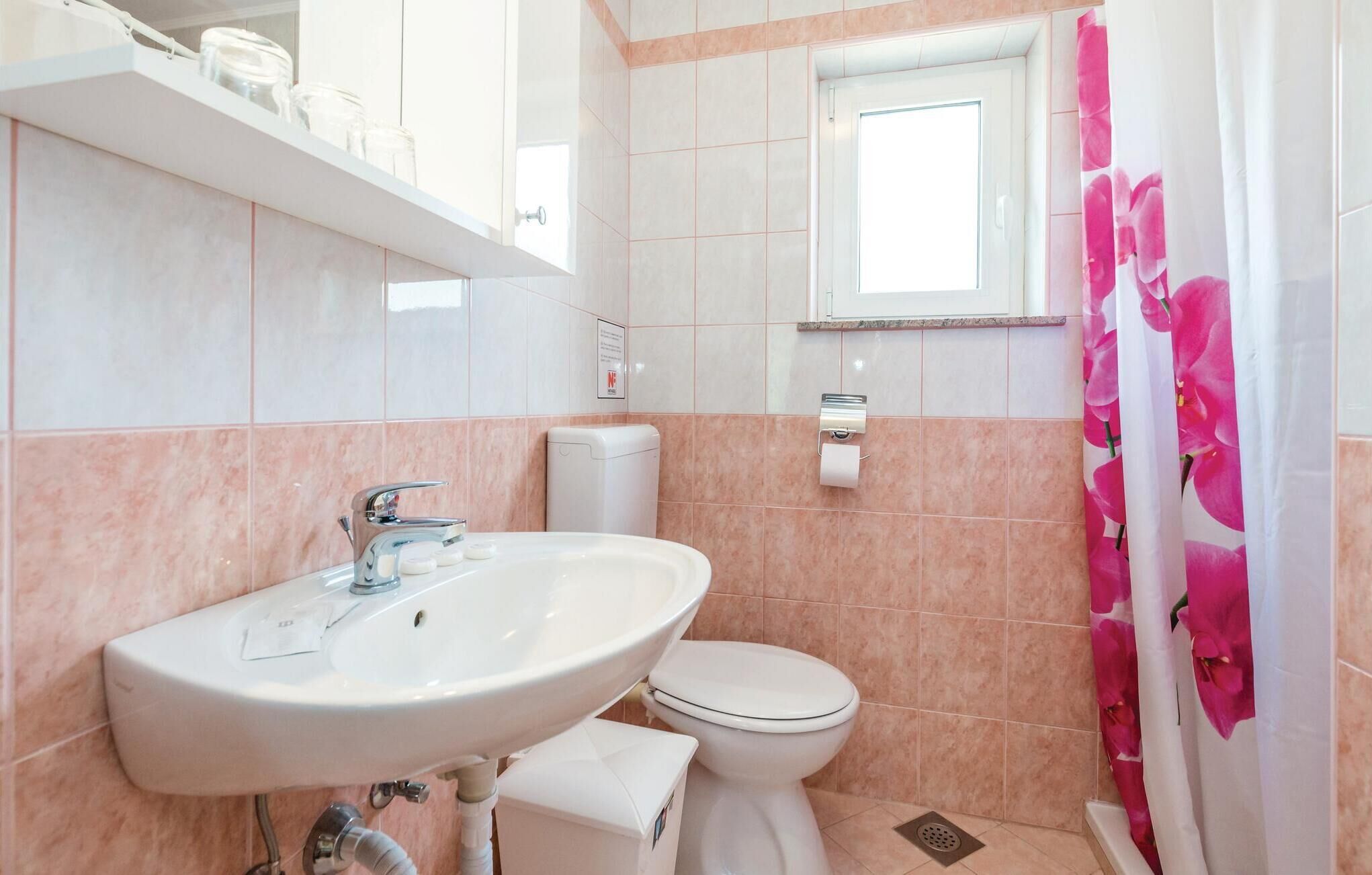 Une salle de bain équipée d’un lavabo, de toilettes et d’un rideau de douche.