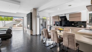 Une cuisine moderne avec un plancher en bois foncé, un coin repas avec des chaises rembourrées et une vue sur une piscine.