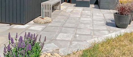 A patio with stone flooring, outdoor furniture, and potted plants.