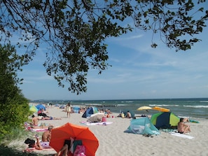 Une scène de plage avec des tentes, des parasols et des gens qui se détendent sur le sable.