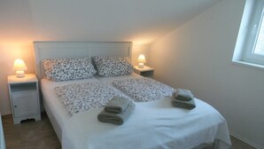 Een net opgemaakt bed met bloemenkussens en twee bedlampjes.
