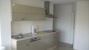 Een kleine keuken met een spoelbak, een koffiezetapparaat en een fornuis.