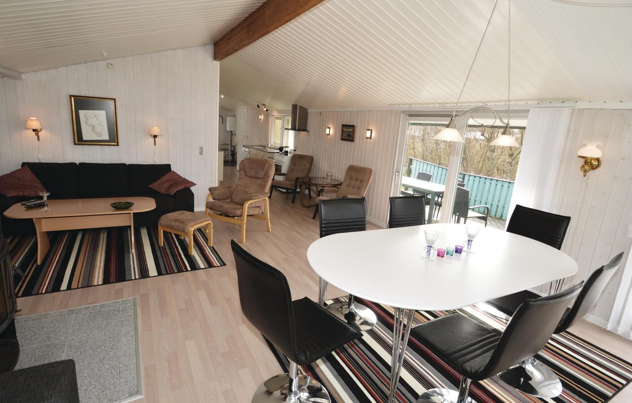 A modern living room with a sofa, chairs, a dining table, and a kitchen in the background.