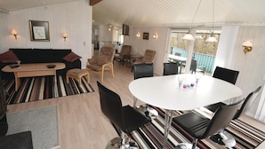 A modern living room with a sofa, chairs, a dining table, and a kitchen in the background. - Cozy home in Løkken with sauna (Løkken)