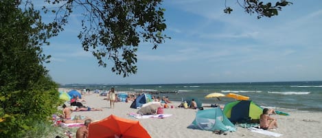 A beach with people sunbathing, umbrellas, and tents.