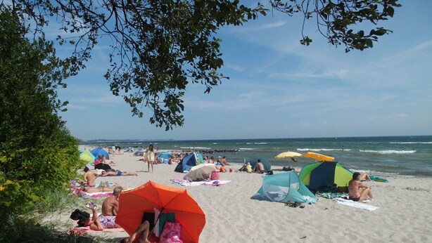 A beach with people sunbathing, umbrellas, and tents. - VO 2; 1-space; EC; Terrace; 25m² - Gästehaus Vogelsang (Sierksdorf)