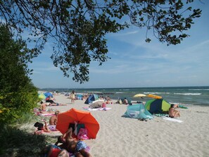 A beach with people sunbathing, umbrellas, and tents.