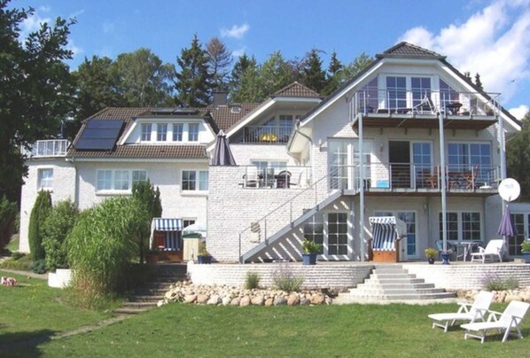 A two-story house with a balcony, a staircase, and a lawn.