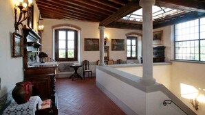 A spacious room with a high ceiling, wooden beams, and large windows.