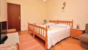 Ein Schlafzimmer mit einem hölzernen Bett, einem Nachttisch, einem Sessel, einem Fernseher und einer Tür.