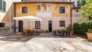 An outdoor patio area with a table and chairs, a white umbrella, and potted plants. - Amazing home in Capannoli PI with WiFi (Capannoli PI)