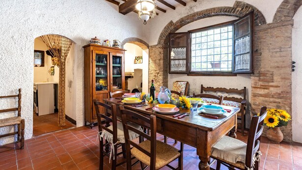 A rustic dining area with a wooden table, chairs, and a cabinet with glass doors. - Amazing home in Capannoli PI with WiFi (Capannoli PI)
