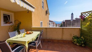 Una terraza con mesa lista para comer, vista a una torre y una valla verde.