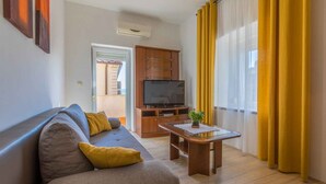 Una sala de estar con un sofá, una mesa de centro, un televisor y un mueble de madera.