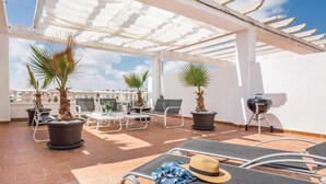 Una terrazza sul tetto con posti a sedere all'aperto, piante in vaso e un barbecue.