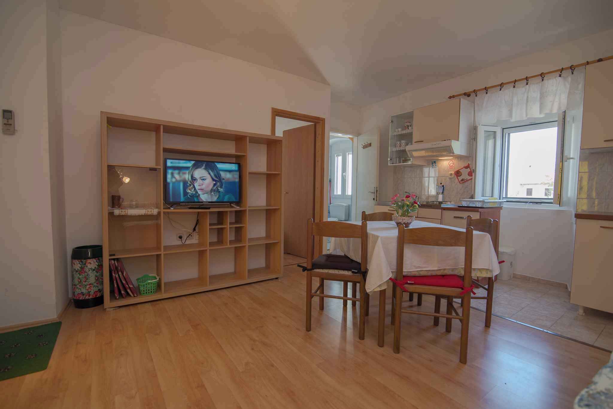 Ein kompakter Wohnbereich mit Essplatz, Fernseher und Küchenzeile.