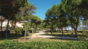 A pathway lined with trees leading to a building with a white facade and a blue roof. - Gorgeous apartment in Argeles sur Mer (Argeles sur Mer)