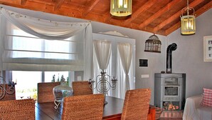 A cozy room with wicker chairs, a dining table, a fireplace, and a large window with curtains. - El Topo, Puntagorda, Spain (Puntagorda)