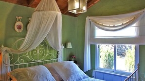 A bedroom with a canopy bed, a window with curtains, and a view of greenery outside. - El Topo, Puntagorda, Spain (Puntagorda)