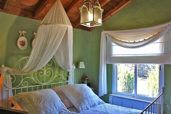A bedroom with a canopy bed, a window with curtains, and a view of greenery outside. - El Topo, Puntagorda, Spain (Puntagorda)