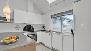 A modern kitchen with white cabinets, a built-in oven, a sink, and a window with blinds.