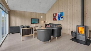 A modern living room with a fireplace, wooden walls, and a large window.